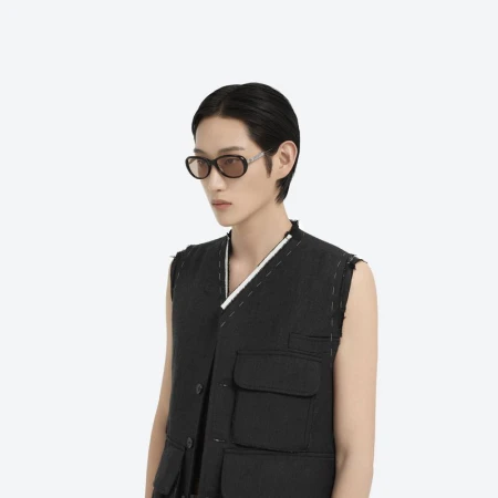 Model wearing dark sunglasses and black vest against a plain white background for Maison Margiela x Gentle Monster collaboration.