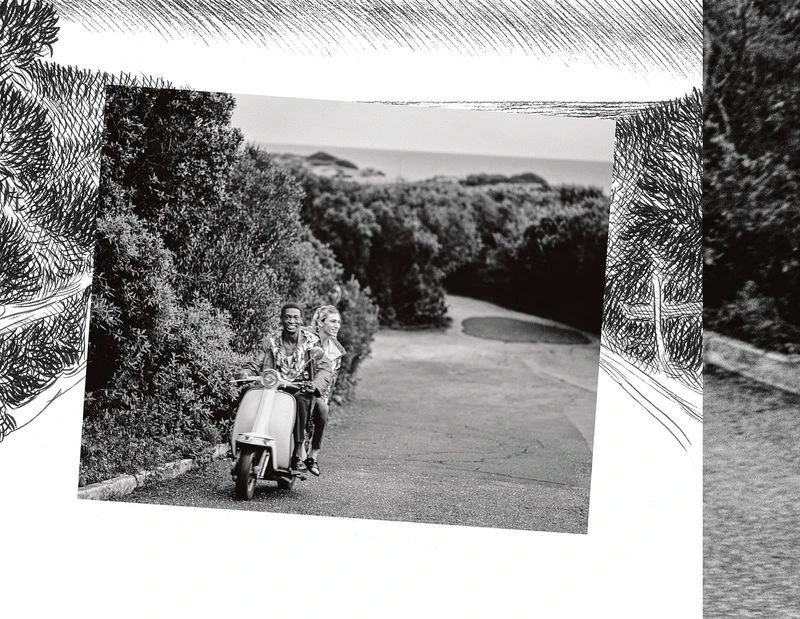 Black and white photo of a smiling man and woman riding a scooter down a road lined with trees, creating a travel or lifestyle image.