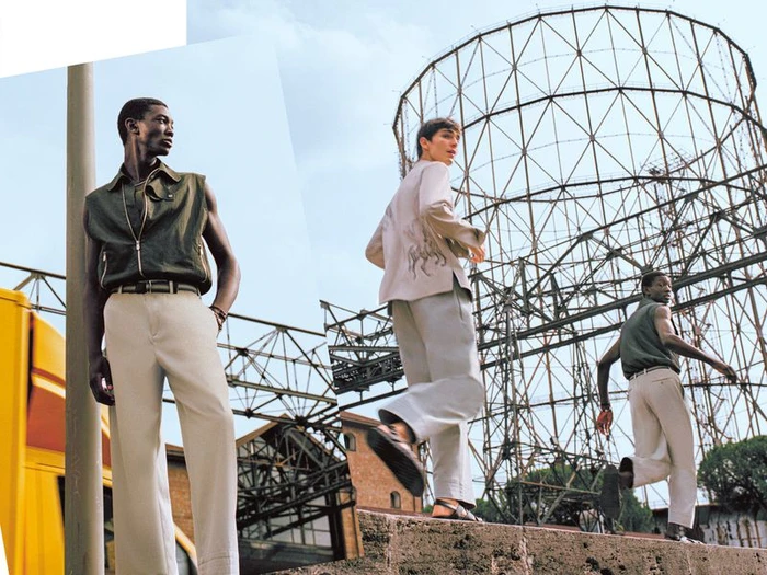 Three male models in contemporary menswear posing near industrial framework structures for Hermès Le Monde d'Hermès 86.