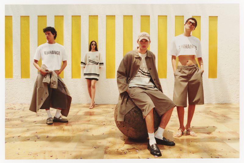 Four fashion models pose outdoors in coordinated, casual apparel. A wall with yellow stripes is in the background.