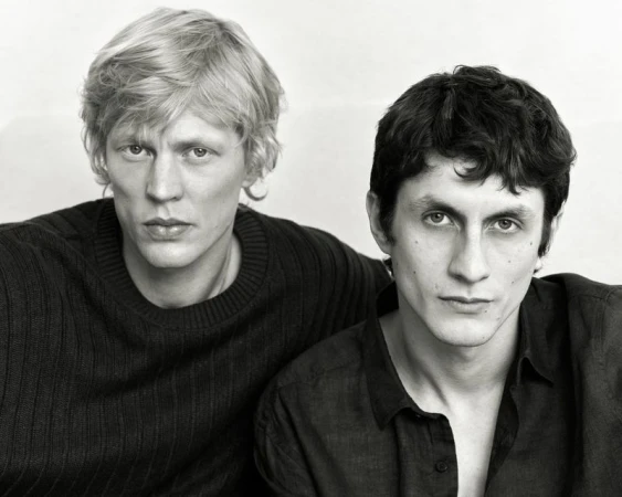 Monochrome portrait of two male models with dark clothing posing against a plain background for Massimo Dutti.