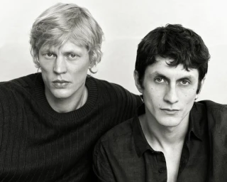 Monochrome portrait of two male models with dark clothing posing against a plain background for Massimo Dutti.