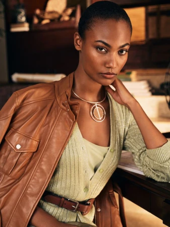 Model wearing a brown leather jacket and green knit cardigan with a gold statement necklace for Ralph Lauren