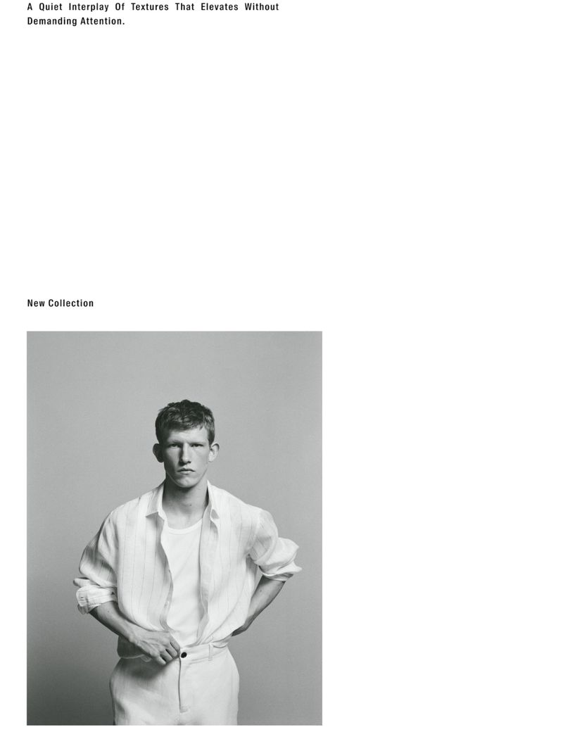 A black-and-white portrait of a young man wearing a linen shirt, standing against a gray background in a fashion-editorial style.