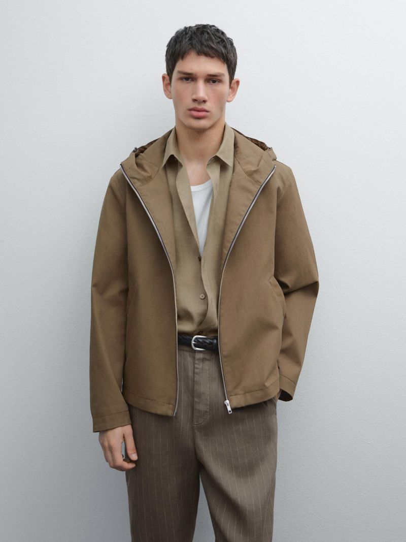 Male model wearing a hooded brown jacket, khaki shirt, and trousers against a neutral background for Massimo Dutti