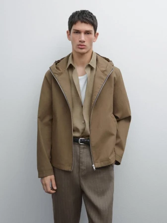 Male model wearing a hooded brown jacket, khaki shirt, and trousers against a neutral background for Massimo Dutti