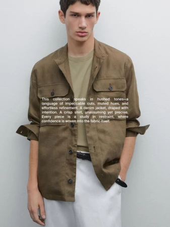 Male model wearing an unbuttoned olive green overshirt and white trousers against a plain light grey background.