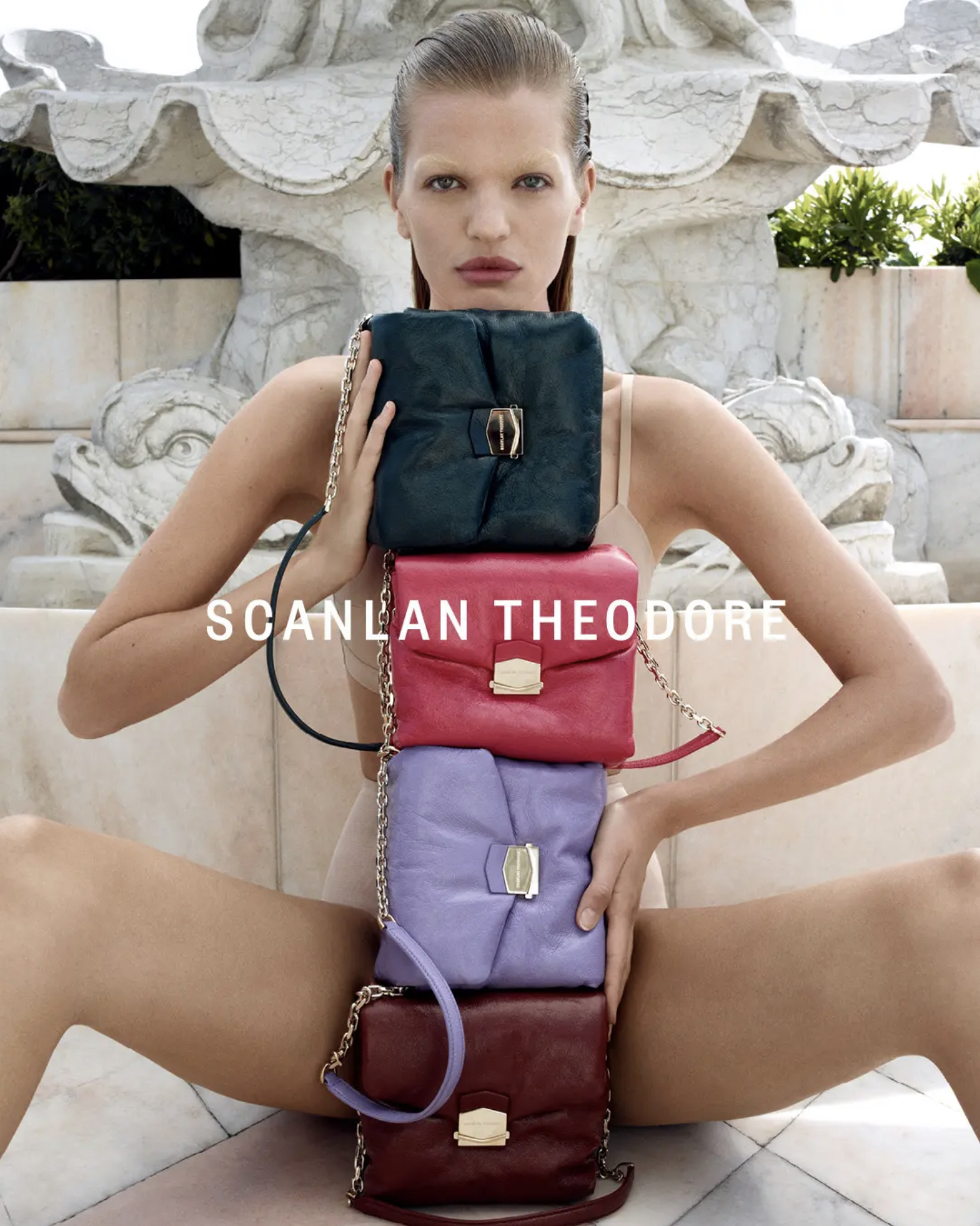 A fashion image displays a woman in a neutral bodysuit outdoors, balanced with four colorful handbags and accessorized with gold chains.