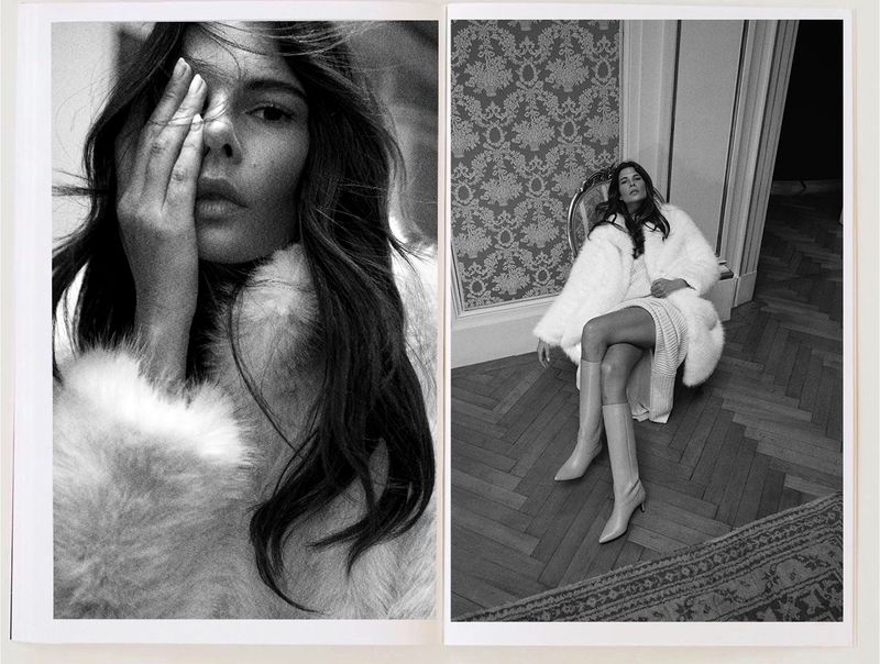Black and white fashion shot featuring a model in a fur coat with floral wallpaper and parquet flooring in the background.