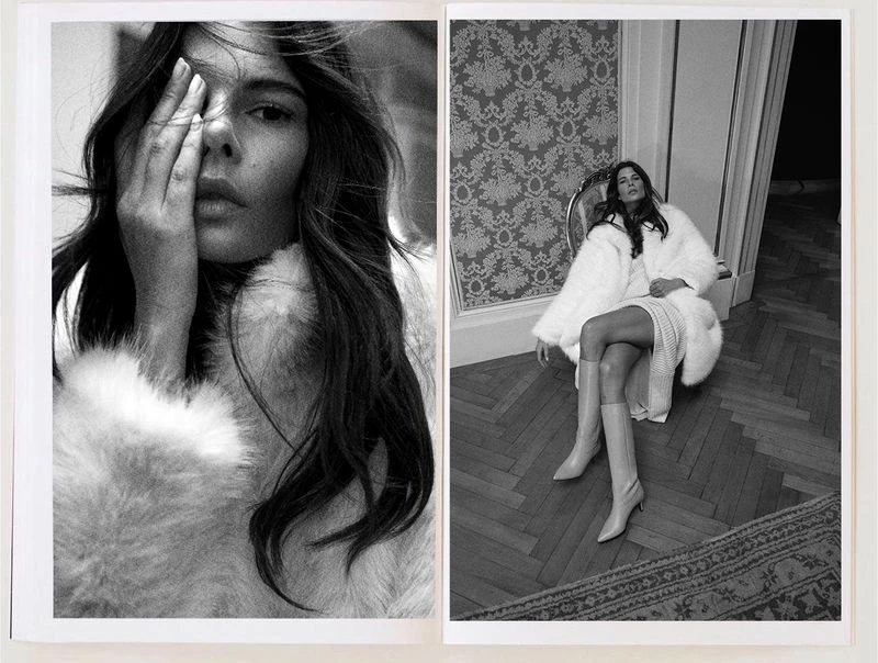 Black and white fashion shot featuring a model in a fur coat with floral wallpaper and parquet flooring in the background.