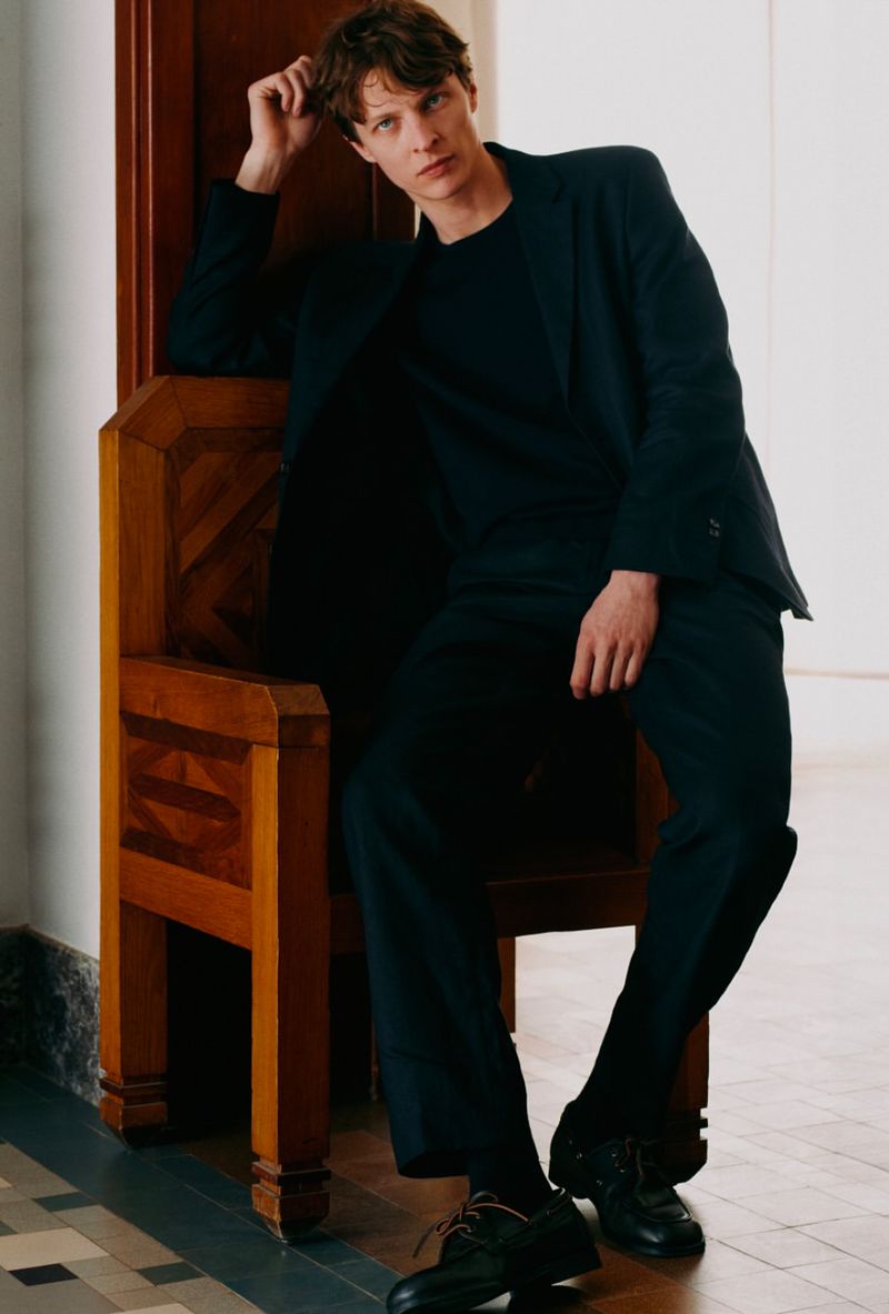 Model Tim Schuhmacher seated on an ornate wooden chair in a dark suit for Massimo Dutti