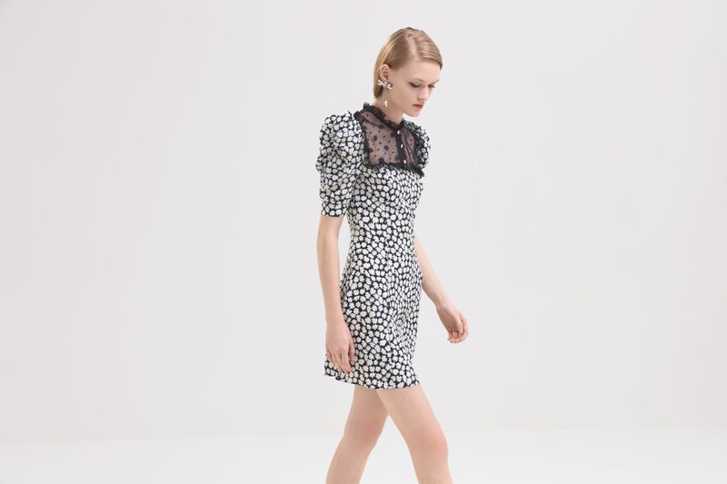 Elegant woman in black and white floral mini-dress and statement earrings in white photo studio. Fashion photography, studio shot.