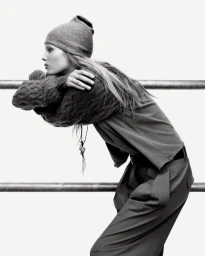 Model Ida Heiner leaning on a railing wearing a knit beanie and sweater for Zara IDA project