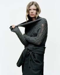 Model Ida Heiner wearing a dark grey cable-knit sweater against a plain white background for Zara project IDA.