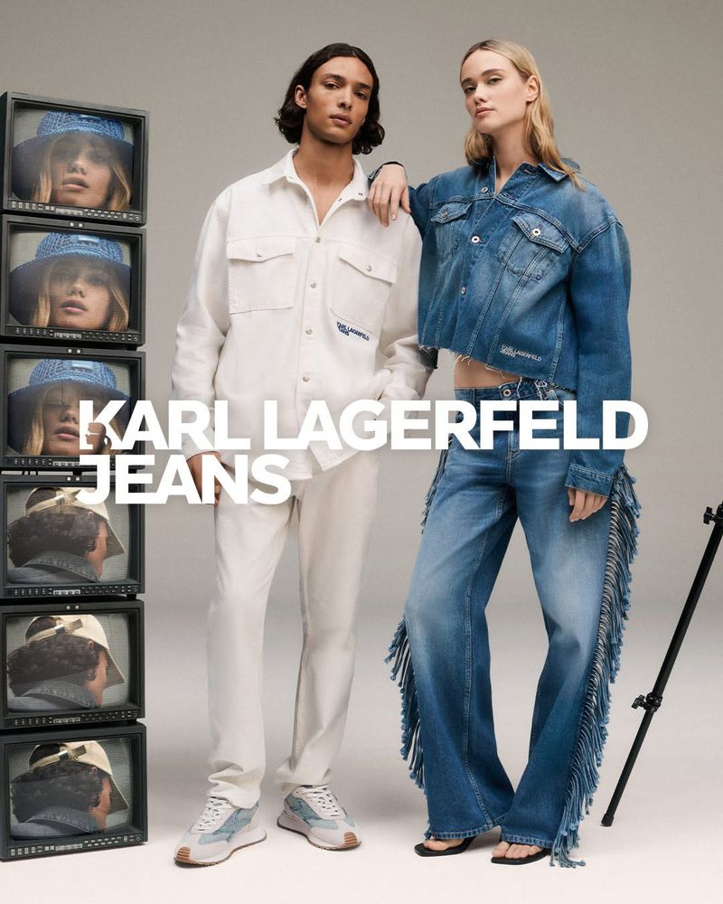 Two fashion models showcase Karl Lagerfeld Jeans in a studio setting with vintage TVs displaying model faces, promoting the brand's latest collection.