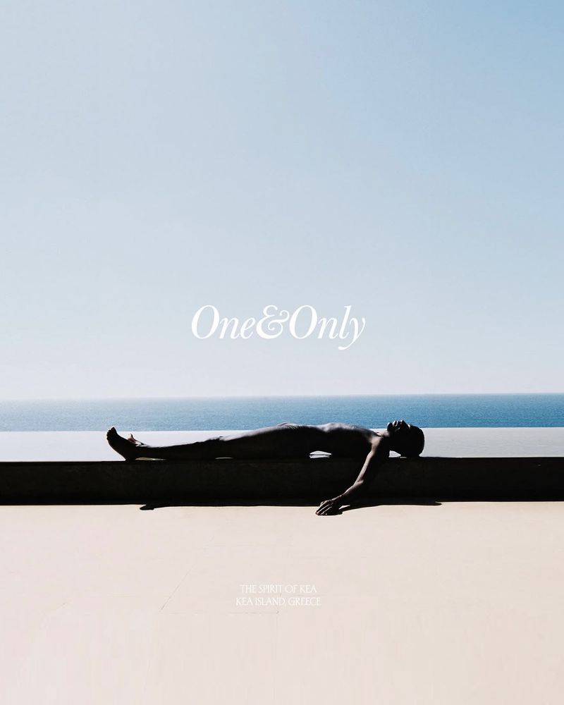 Adult lying on a concrete ledge next to the ocean under a clear sky. Conceptual image featuring lifestyle and travel themes.