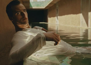 Model Parker Van Noord reclining in a pool wearing a white shirt for Zara Man Spring edition, photographed by Daniel Archer.