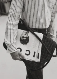 Close-up of a person wearing a striped shirt, holding a black woven handbag and magazine for Icon Magazine Australia.