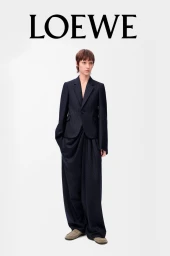Model wearing a dark pinstripe suit and trousers against a plain white studio background with Loewe typography above