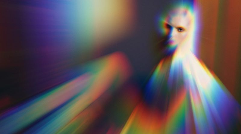 Surreal portrait of a human face with chromatic aberration and rainbow light streaks creating a dreamlike, distorted, and colourful atmosphere.