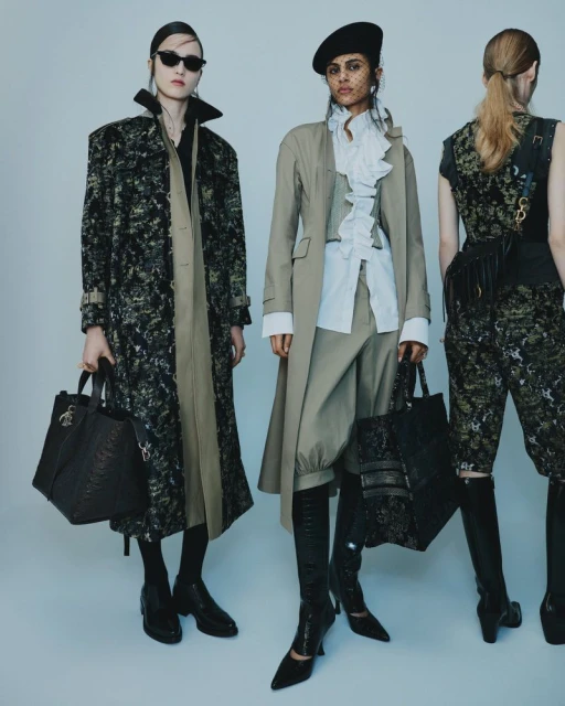 Three fashion models showcase designer coats, trousers, and handbags in a studio setting, wearing sunglasses and berets for a modern look.