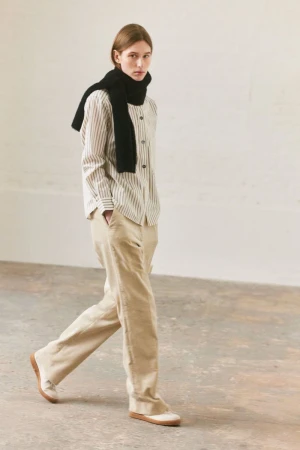 Model walking in a striped shirt, beige trousers, and a black scarf for Margaret Howell F/W 25.