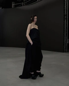Model wearing a structured black strapless top and matching trousers against a dark studio background