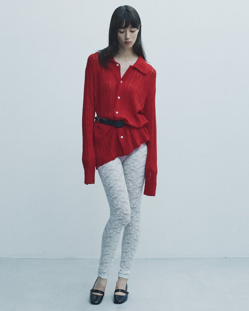Woman in red button-down shirt and white leggings poses against a white background in a fashion shot with full figure and long shot.