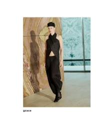Model in black wrap top and pleated trousers standing against patterned marble wall for Massimo Dutti Studio