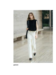 Model wearing a black top and white trousers walking along a stone walkway for Massimo Dutti Studio 2025