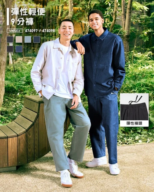 Two young adult men model casual clothing outdoors in a sunlit park setting, showcasing a contemporary fashion style with natural light.