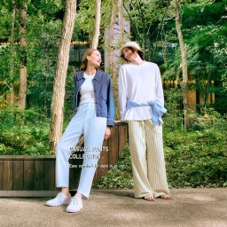 Two female models posing outdoors in a lush park setting wearing casual pants collection apparel by Uniqlo