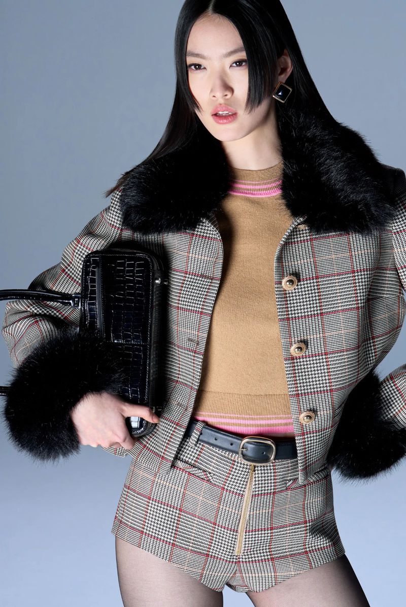 A stylish Asian model poses in a plaid jacket with fur trim, paired with matching shorts, accessorized with a black purse and belt.