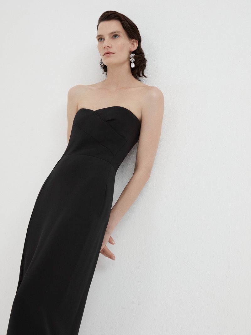 Model wearing a black strapless midi dress against a plain white studio background.