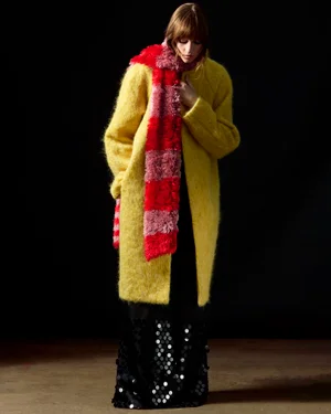 Model wearing a fuzzy yellow coat and a textured red scarf against a dark background for Zankov FW25.