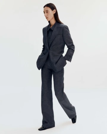 Model wearing a dark grey tailored suit jacket and matching trousers against a white seamless background.