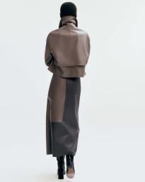 Model seen from behind wearing a brown leather jacket and matching skirt against a white background