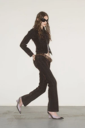 Model wearing dark fitted jacket and trousers with sunglasses posing against a plain wall for KNWLS lookbook