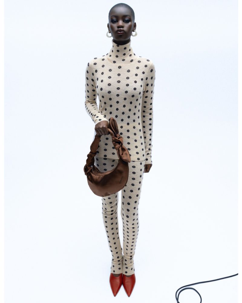 Full-length shot of an African American fashion model in a polka dot outfit, accessorized with hoop earrings, a purse, and red heels.