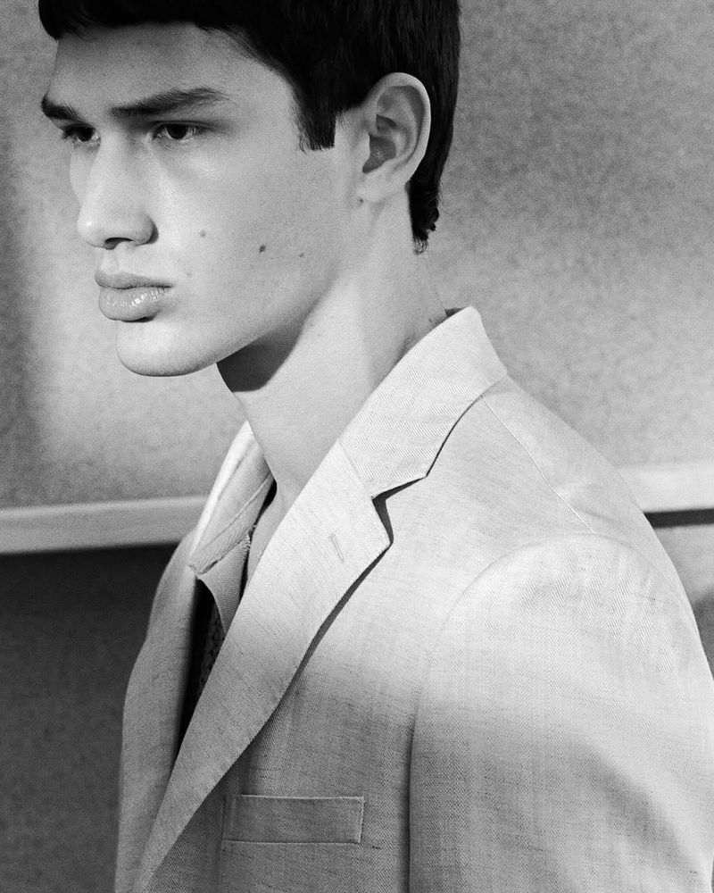 Monochrome portrait of a handsome man in a linen blazer. Close-up studio shot with soft lighting. Classic menswear aesthetic.