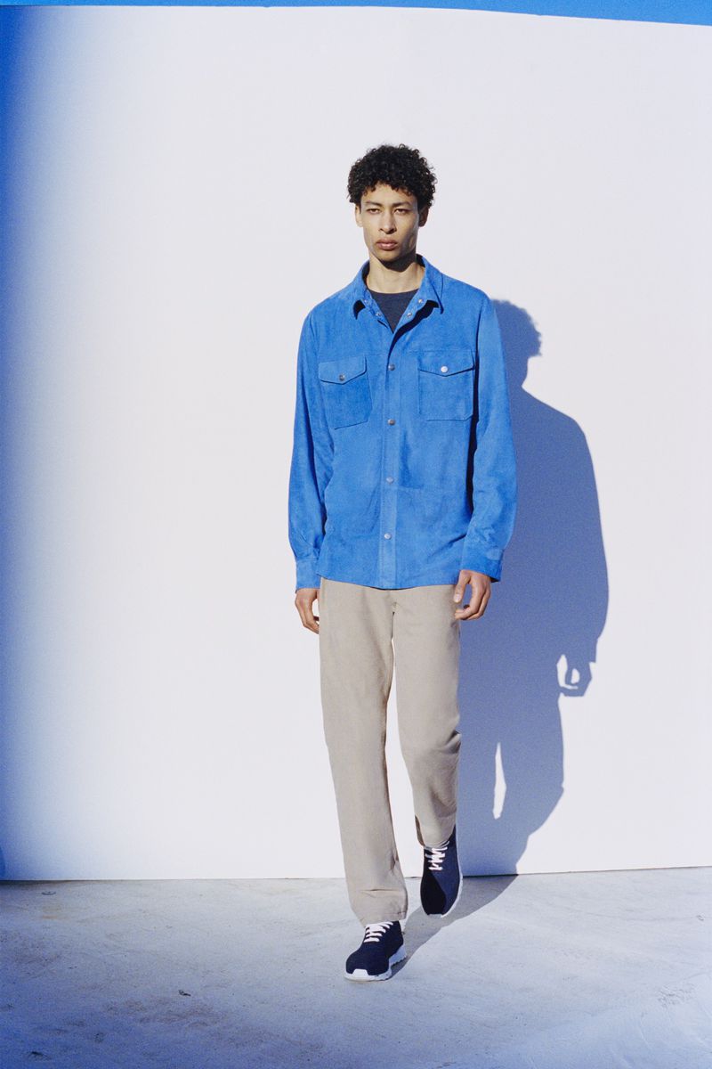 Model Luthando Ngema in a blue shirt and beige trousers against a bright white background for Bergdorf Goodman.