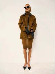 Model wearing brown suede jacket, matching turtleneck dress, and black leather gloves against a white background.