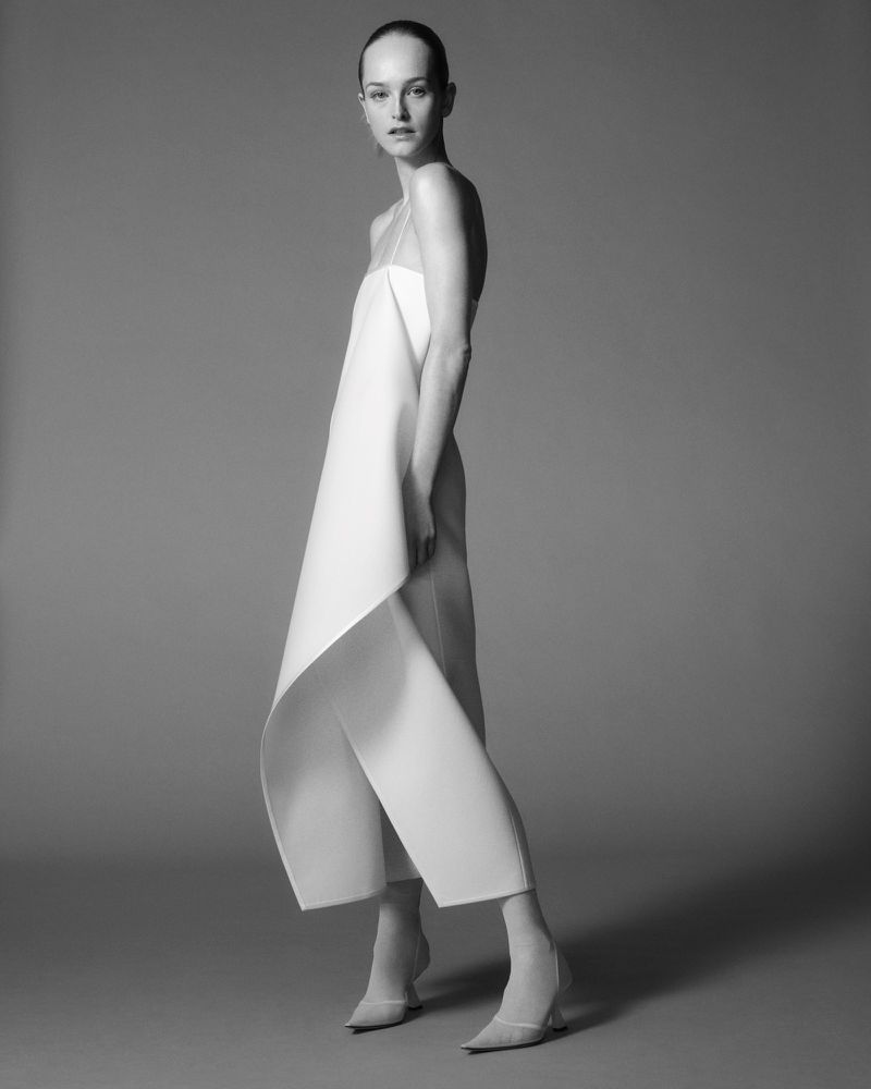 Model Jean Campbell in a structured white dress against a neutral grey studio background for Giada Fall Winter 2025 lookbook