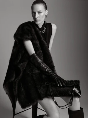 Model Julia Nobis wearing a black fur wrap and leather gloves holding a handbag against a grey seamless studio backdrop for Scanlan Theodore
