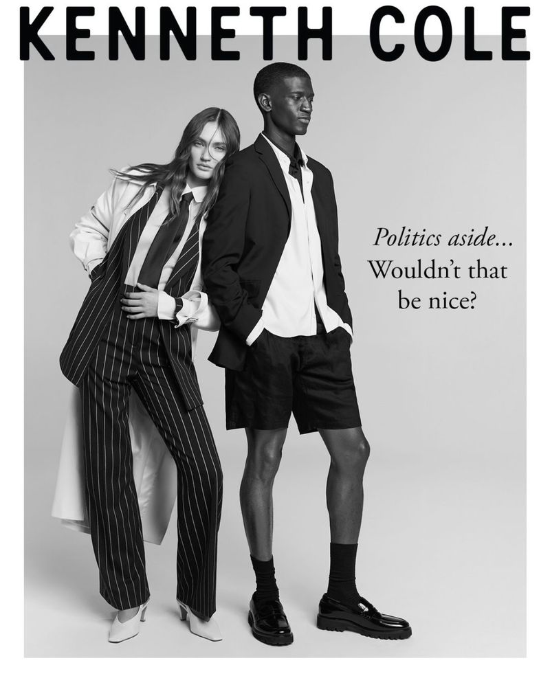 Fashion editorial photo: a biracial couple poses in Kenneth Cole suits against a studio backdrop, showcasing contemporary style and bold tailoring.