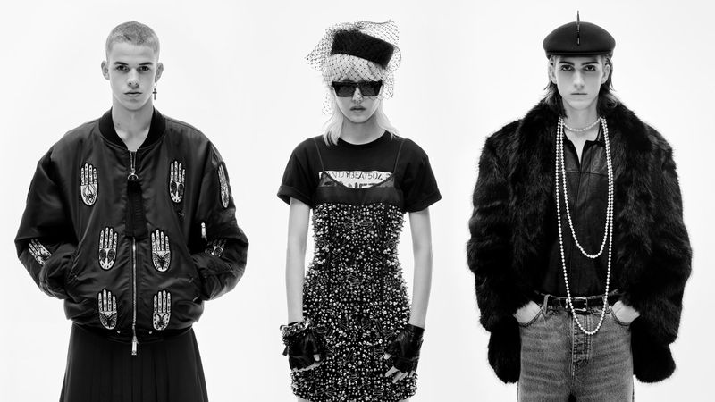 Three fashion models pose in a stark white photo studio. The models wear hats and outerwear, including a bomber jacket and fur coat.
