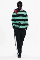 Model wearing a black and mint striped top and black trousers against a white seamless background for Stefan Cooke F/W 25.