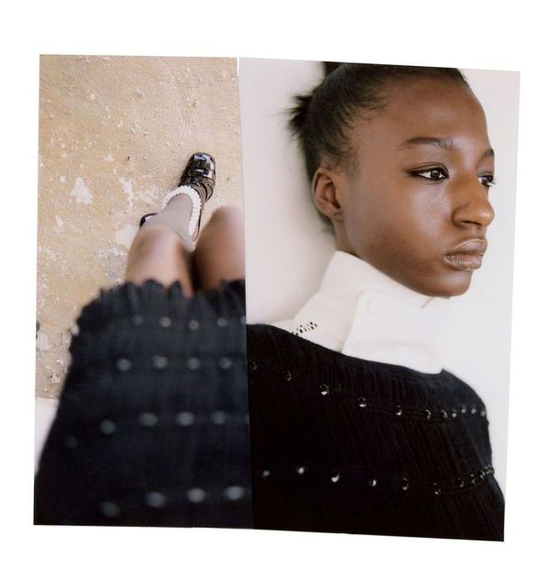 Fashion shot featuring an African American woman in a black top with a white collar, alongside a leg with a black shoe on a beige surface.