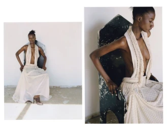 Black model wearing an off-white textured halter dress seated on a dark patterned chair against a plain wall.