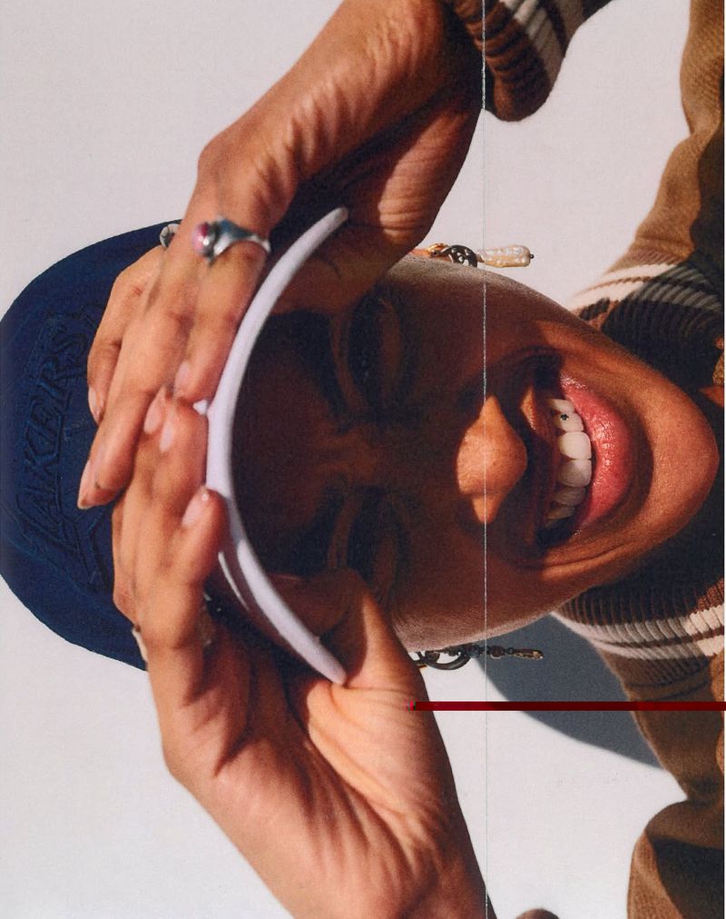 Close-up portrait of model Daeshawn Montgomery wearing a blue baseball cap and brown sweater for Tommy Hilfiger by Petros.